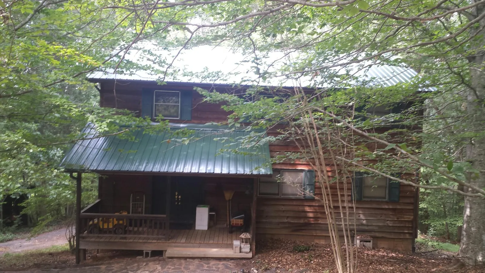 Green metal roof and covered porch on a log cabin in Lawrenceville