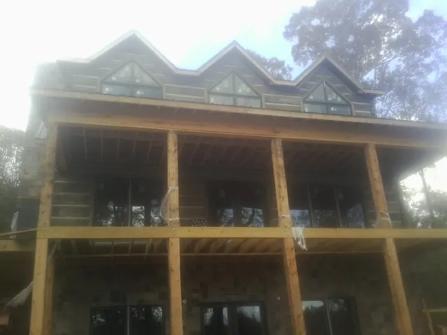 Dormers and porch framing on a large log home under construction — Roof Coating work by our crew in Lawrenceville